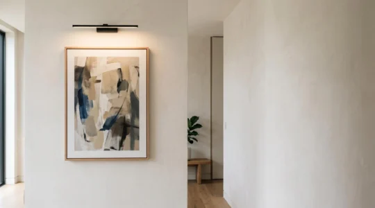 Applique murale élégante orientée vers un tableau encadré dans un intérieur contemporain, créant un éclairage doux sans reflet