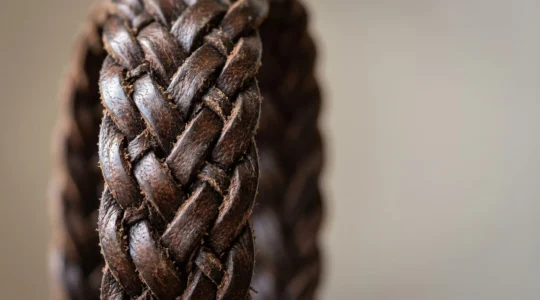 Gros plan détaillé sur un bracelet en cuir tressé naturel présentant une texture authentique et une patine élégante