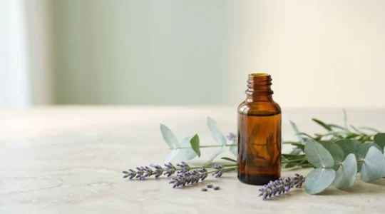 Flacon d'huile essentielle posé sur une surface naturelle avec des éléments végétaux apaisants