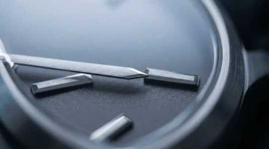 Gros plan détaillé d'une montre minimaliste élégante avec cadran épuré sous éclairage LED froid, mettant en valeur la lisibilité des aiguilles et la finition métallique sobre