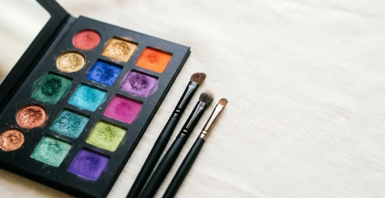 Palette de fards à paupières aux couleurs vives disposée avec pinceaux de maquillage